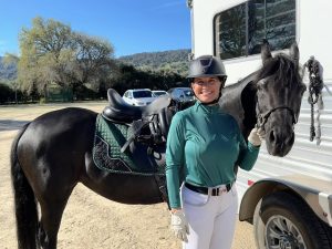 Stacie Rice posing with her horse who is tacked up for a dressage show.